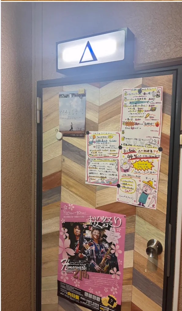 上に明かりのついたΔの看板がある店の扉