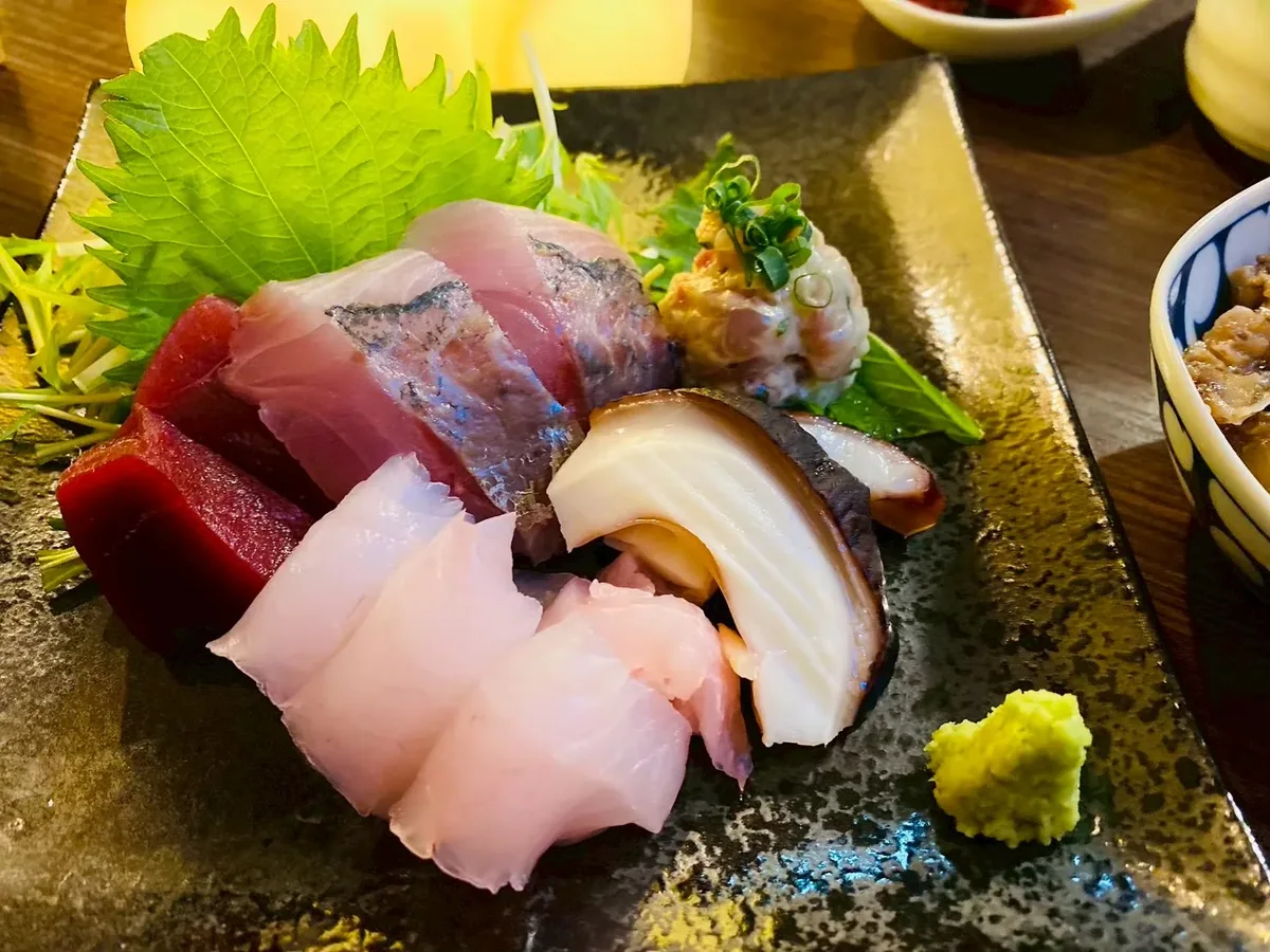 濃い色の皿に盛られた刺身の提供例